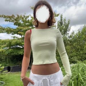 NA-KD top - Trendig ljusgrön ribbad topp från NA-KD med asymmetrisk design. Ena sidan är långärmad medan den andra är ärmlös. Helt oanvänd, säljer för att jag glömde lämna tillbaka den. Är en XS men passar även S. Nypris: 399 kr. Säljer för 149 kr. Hör gärna av dig för fler bilder/frågor! 😊☀️🌻