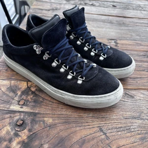 Mörkblå mockasneakers från Diemme - Snygga mörkblå sneakers från Diemme i mocka med vita sulor och coola metallhakar för snörningen. Skorna har rund tå och blå skosnören, samt detaljer i svart skinn på plösen. Skorna är använda men i bra skick, inga defekter och går att fresha upp ännu mer. Köpte för 3799, box ock kvitto finns. Mitt pris 2000 kr.