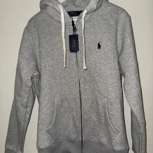 Grå hoodie och byxor från Polo Ralph Lauren - Helt ny Ralph Lauren Tracksuit i storlek M. Tag finns kvar. Hoodien och byxorna kan köpas separat om så önskas.