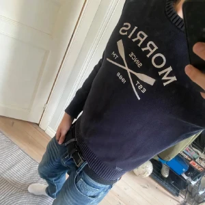 Mörkblå stickad tröja från Morris - Snygg mörkblå stickad tröja från Morris med vit logga och korsade åror framtill. Tröjan har rund halsringning, ribbade muddar och är långärmad. Tröjan är i bra skick och knappast använd, nypris ca 1500. Priset är diskuterbart.