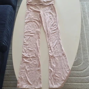 Ljusrosa bootcut byxor Gina Tricot - Supersköna ljusrosa bootcut byxor från Gina Tricot i mjukt bomullsmaterial. Hög midja och stretchig passform som sitter snyggt över höfterna och släpper ut vid benen. Perfekta för en chill och trendig look.