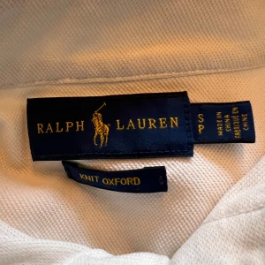 Vit oxfordskjorta från Ralph Lauren - Klassisk vit oxfordskjorta från Ralph Lauren med broderad logga på bröstet. Skjortan har lång ärm, knappar framtill och button down-krage. Tillverkad i mjuk bomull som ger en clean och tidlös look. Skjortan är i storlek S men passar även XS