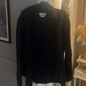 Svart linneskjorta från Strömberg - Snygg svart skjorta från Strömberg i linnemix. Klassisk krage, långärmad och med knäppning framtill. Perfekt för dig som gillar en stilren och enkel look. Skjortan har en bröstficka och är riktigt skön tack vare linnematerialet.