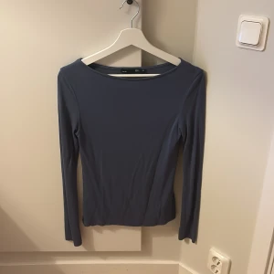 Blå långärmad topp från Lager 157 - En stilren blå långärmad topp från Lager 157 med rundad halsringning. Modellen är figurnära och enkel, perfekt att matcha med jeans eller kjol. Tunt och stretchigt material som känns skönt mot huden.