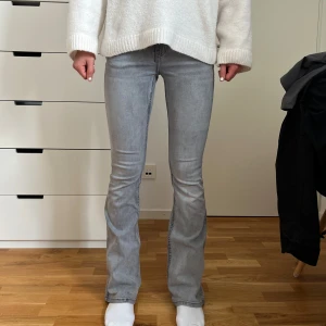 Ljusgrå bootcut jeans - Snygga ljusgrå jeans med bootcut passform och klassiska fickor både fram och bak. Jeansen har en smalare passning upptill och lätt utsvängda ben, vilket ger en modern och stilren look. Perfekta att matcha med en oversized tröja eller hoodie.