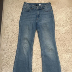 Ljusblå bootcut jeans - Säljer ett par ljusblå jeans med bootcut-modell och klassisk femficksdesign. Jeansen har hög midja och är tillverkade i mjukt denimtyg. Perfekta för dig som gillar en retro vibe och vill ha ett par jeans med lite utsvängda ben.
