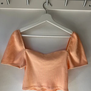 Orange ribbad croppad topp H&M - Säljer en croppad topp från H&M i ljusorange färg/persikofärg. Toppen har korta puffärmar, fyrkantig urringning och är ribbad i materialet. Toppen är inte genomskinlig i materialet. Den är i mycket fint skick, och är knappt använd!