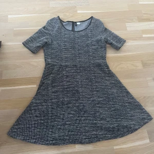 Feminin kortklänning från Divided - Kortklänning från Divided. Klänningen har rund halsringning, korta ärmar och lätt utställd kjol. Ger snygg figur. Perfekt för dig som gillar enkel men snygg stil. Har tidigare haft fejkskinn runt halskänningar o knäppe, men det har fnasat bort, men är lika snygg utan!