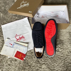 Christian Louboutin Skor - Exklusiva sneakers från Christian Louboutin i mörkblå mocka med den ikoniska röda sulan. En tidlös och lyxig design som kombinerar stilren elegans med högsta premiumkvalitet. Perfekta för både vardag och mer dressade tillfällen.  ♦️ Helt nya – aldrig använda ☑️ ⚜️ Storlek 43 – normal passform ☑️ ♦️ Klassisk Louboutin-design med röd signatursula ☑️ ⚜️ Levereras med originalkartong, dustbag & alla tillbehör ☑️  📦 Snabb leverans & trygg affär 