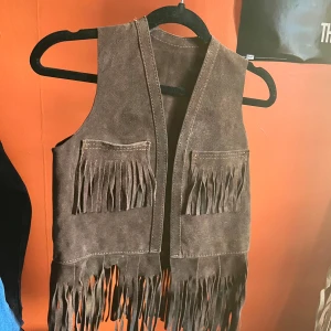 Mocka väst - Jätte söt brun mocka väst med fransar. Den är i mycket bra kvalité och skulle passa XXS bra. Jag har aldrig använt den då den var för liten men den har nog definitivt använts förr, även fast det inte syns så mycket!