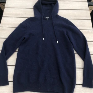 Mörkblå hoodie i kashmir från Vernando - Mysig mörkblå hoodie från Vernando i mjuk och Perfekt för dig som gillar en clean och stilren look med premiumkänsla. Jag säljer tröjan då de är för liten, den är i storlek S. Vid minsta lilla fråga så kan du höra av dig! Tröjan är i väldigt fint skick! Priset kan självklart diskuteras