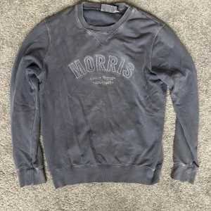Blå sweatshirt från Morris - Snygg blå sweatshirt från Morris med broderad logga på bröstet. Tröjan har rund halsringning, ribbade muddar och klassisk passform. Perfekt för en avslappnad och stilren look. Storlek S. Urtvättad