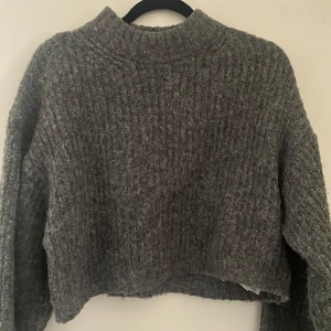 Supersöt stickad tröja - Supermysig och söt grå stickad tröja från Gina Tricot. Den är lite croppad- använd ett fåtal gånger💗Storlek XXS. Perfekt nu till höst och vinter säsongen🍂❄️Vid mer info osv hör gärna av dig🫶🏼