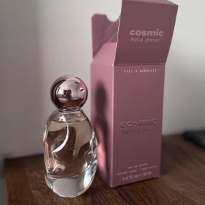 Cosmic Kylie Jenner Eau de Parfum 50ml - Cosmic av Kylie Jenner är en parfym i en unik, skulptural glasflaska med en metallisk, roséfärgad klotformad kork. Flaskan rymmer 50 ml och är helt ny och oanvänd. Köpt för 740kr. 