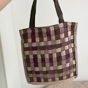 Vävd totebag i skinn - Unik shoppingväska i vävd design med rutor i lila, grön, beige och grå. Väskan har två mörkgröna handtag och stängs med tryckknapp. Tillverkad i mjukt skinn. ❤️No brand, handmade.