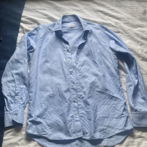 Blå mönstrad skjorta från Stenströms - Snygg blå skjorta från Stenströms med diskret småmönstrat tyg och fitted body-passform. Skjortan är i mjuk bomull och har klassisk krage, knappar framtill och långa ärmar med manschett. Perfekt för dig som gillar stilrena detaljer och bekväm känsla. Orkar inte stryka den o ta fina bilder men den är i jätte bra skick och om ni vill ha mer info om den storleksvis så passar den mig skit bra o jag använder mig vanligt vis storlek M och S på kläder