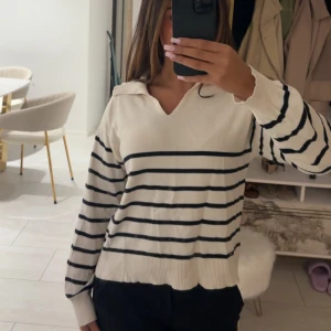 Randig vit tröja - Vit tröja från Gina Tricot med svarta horisontella ränder och v-ringad krage. Tröjan har långa ärmar och ribbade muddar. Perfekt för dig som gillar en klassisk och chill stil.