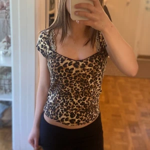 Leopardmönstrad topp från Nelly - Säljer en snygg leopardmönstrad topp från Nelly! med v-ringning och spetsdetaljer vid halsen. Toppen har korta ärmar och är figurnära, perfekt för dig som vill sticka ut med ett djurmönster. Färgerna går i beige, brunt och svart❤️❤️