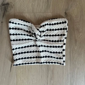 Randig bandeau tubtopp från Amisu strl Xs - Snygg bandeau tubtopp från Amisu i storlek XS. Toppen är vit/beige med svarta ränder i ett coolt mönster och har en twistad detalj framtill. Super fin 💗