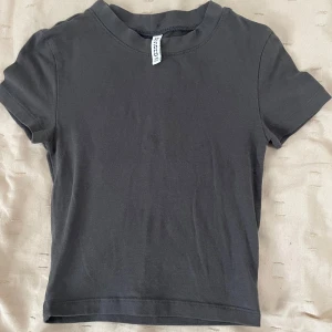 Svart basic t-shirt från H&M Divided - En svart, enkel och klassisk t-shirt från H&M Divided. Modellen är kortärmad med rund hals och har en normal passform. Materialet är mjuk bomull som känns skönt mot huden. Perfekt till jeans eller shorts för en chill look.