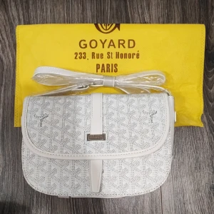 Helt ny vit axelväska  - Snygg vit axelväska med klassiskt mönster och justerbar axelrem. Väskan har lock med magnetstängning och detaljer i vitt skinn. Perfekt storlek för det viktigaste och en riktigt clean look.