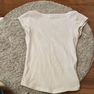 Vit linnetopp  - Säljer en stilren vit ribbad linnetopp med smickrande passform. Toppen har korta ärmar. Perfekt till jeans eller kjol för en fräsch look. Materialet är mjukt och stretchigt för maximal komfort.