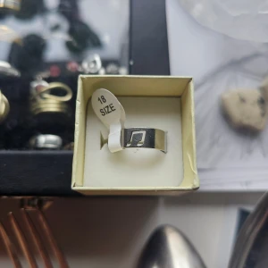 Silverring med utskuren not - Cool silverfärgad ring i storlek 18 med en utskuren musiknot på framsidan. Ringen har en bred, slät design och passar perfekt för dig som älskar musik och vill ha en unik detalj i din stil. Rostfritt stål, 18.1 mm