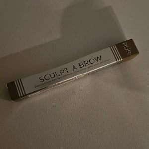 PÜR Sculpt A Brow Light ögonbrynspenna - PÜR Sculpt A Brow i färgen Light är en vattenfast ögonbrynspenna med kräm-till-puder formula. Pennan har en snedställd borste för att enkelt fylla i och skulptera brynen. perfekt för att skapa markerade och naturliga bryn.