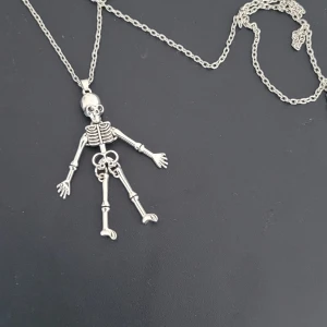  Helt ny Halsband med skelettberlock i silverfärg - Unikt halsband med en detaljerad skelettberlock i silverfärg. Kedjan är tunn och berlocken har rörliga leder vilket ger ett coolt och lekfullt intryck. Perfekt accessoar för dig som gillar edgy och annorlunda smycken.
