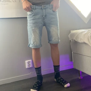 Ljusblå jeansshorts från LAB Industries - Säljer ett par ljusblå jeansshorts från LAB Industries med klassisk femficksdesign och uppvikta benslut. Shortsen har normal passform och är tillverkade i mjukt denimtyg. Perfekta för chill dagar och sommarhäng.