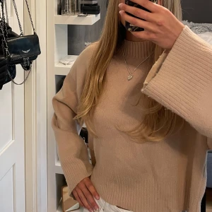 Beige stickad tröja - Beige stickad tröja med breda, långa ärmar och ribbade muddar vid ärmslut, halsringning och nederkant. Står ingen storlek men skulle säga är en S men passar XS och M också! 