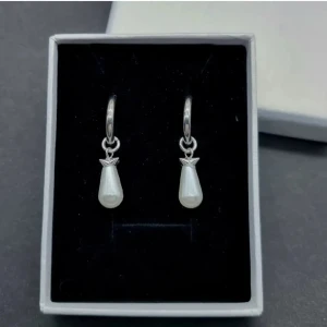 Silvriga örhängen med droppformad pärla - Snygga örhängen i silverfärg med hängande droppformad vit pärla. Ringen är enkel och stilren, medan pärlan ger en elegant touch. Perfekta för dig som gillar klassiska smycken med en modern twist.