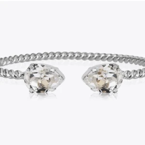 Silverfärgat armband med kristaller - Elegant armband i silverfärg med två stora, klara kristaller i ändarna. Armbandet har en tvinnad design som ger en modern och stilren look. Perfekt för att lägga till lite extra glans till din outfit.