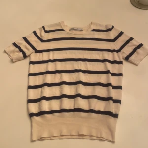Randig kortärmad tröja från Zara - Säljer en stilren randig tröja från Zara i vitt och blått. Tröjan har korta ärmar och en klassisk rund halsringning. Tröjan är i fint skick och är i storlek M