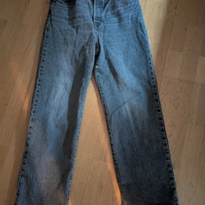 Grå jeans Ribcage Straight Ankle - Säljer ett par grå Levi's Ribcage Straight Ankle jeans. De har en hög midja och rak passform som slutar vid ankeln. Perfekta för en avslappnad stil. Klassisk femficksdesign med knappgylf.