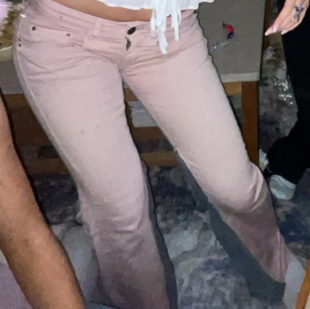 Snygga rosa bootcut jeans med låg midja. Perfekta för en avslappnad stil med en touch av retro. De har en klassisk femficksdesign och en bekväm passform. 37,5 midja rakt över, innerbenslängd 75cm. Farkut & Housut.