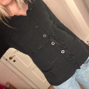 SVART ULL KOFTA - Säljer denna svarta ull kofta från bruuns bazaar. Den är väldigt varm pga den är gjord av ull och jag säljer den på grund av att den inte kommit till användning. Den är i storlek Medium men passar även xs/s pga att man kan knyta den i midjan. Köptes för 600kr säljer för 300kr men priset kan såklart diskuteras❤️ kom privat för flera bilder (har använts 2 gånger)