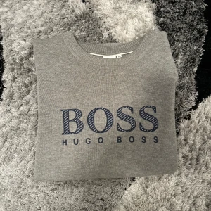 Grå tröja från Hugo Boss - Säljer en  grå tröja i bra skick  från Hugo Boss . Den är stilren med inga fläckar eller skador.