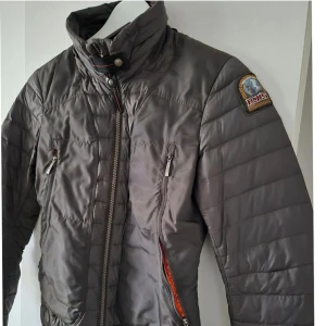 Parajumpers Giuly lightweight  - Säljer en snygg grå dunjacka från Parajumpers med dragkedja och hög krage. Jackan har två praktiska fickor med dragkedjor och en cool patch på ärmen. Perfekt för kyliga dagar! ÄKTA, nypris 3499:-