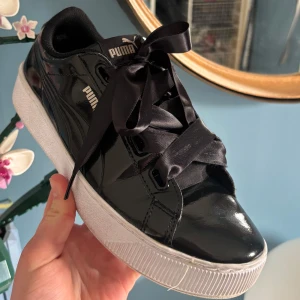 Svarta sneakers från Puma - Snygga svarta sneakers från Puma med glansig yta och breda svarta satin snören. Mycke bra skick är i storlek 40🩵