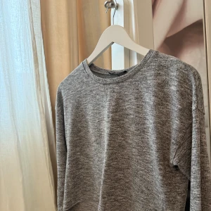 Grå tröja från New Yorker - Säljer en stilren grå tröja från Sisters Point. Tröjan har en rund halsringning och är långärmad, perfekt för en avslappnad look. Materialet är mjukt och bekvämt, vilket gör den idealisk för kyligare dagar.