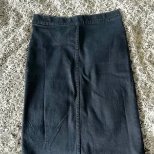 Jeanskjol - Mörkblå jeanskjol med dragkedja baktill. Kjolen har en klassisk design och är även stretchig.