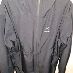 Svart vindjacka från Haglöfs - Säljer en stilren svart vindjacka från Haglöfs. Den säljs på grund av att den inte används. Den är i riktigt bra skick utan några konstigheter. ÄKTA FRÅN XXL