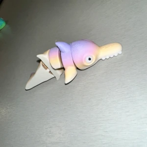 Flerfärgad leksakskrokodil - En flerfärgad leksakskrokodil i pastellfärger som lila, rosa och gul. Kroppen är segmenterad vilket ger den en rörlig design. Perfekt för lek och samling!