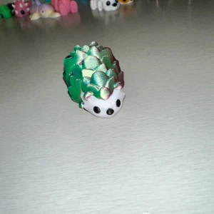 Grön och blå igelkottfigur - Charmig liten igelkottfigur i grönt och blått med vita detaljer. Perfekt som dekoration eller samlarobjekt. Den har en söt design med små, spetsiga detaljer som liknar taggar.