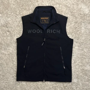 Marinblå Woolrich väst - Västen är mörkblå och från Woolrich, västen är något tunnare och funkar perfekt med en tröja under. Storlek M men passar mer som S.         Skick 9/10