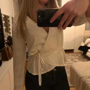 Vit blus - Säljer en stilren vit omlottblus med knytband i midjan. 