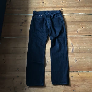 Svarta Levi's 501 jeans - Säljer ett par klassiska svarta Levi's 501 jeans. De har en rak passform och är tillverkade i slitstarkt denim. Perfekta för en stilren look med den ikoniska Levi's-lappen baktill.