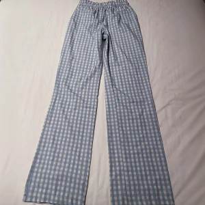 Rutiga byxor från Design by Si - Säljer snygga blå och vita rutiga byxor från Design by Si. Byxorna är raka/lite baggy och har en elastisk midja. Perfekta lounge byxorna. Kontakta mig om du har frågor🩷