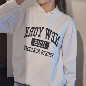 Vit hoodie med tryck - Säljer en vit hoodie med texten 'New York 1999 Sports Academy' tryckt på framsidan. Hoodien är i storlek 160/S💗